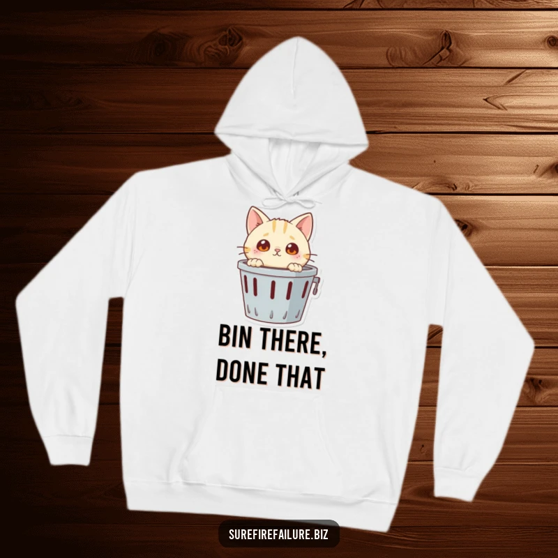 Funny hoodie, a wide-eyed curious cat peeking out from an overturned wastebasket, capturing a moment of playful chaos.